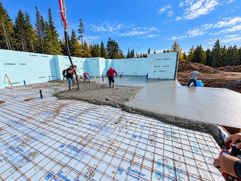 Crew spreading concrete over rebar and foam board during a slab pour, Whiteside